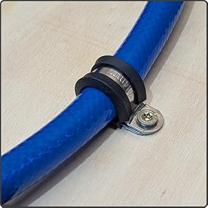 Un tubo blu per l'aria compressa viene fissato a una superficie di legno con una pinza per tubi.